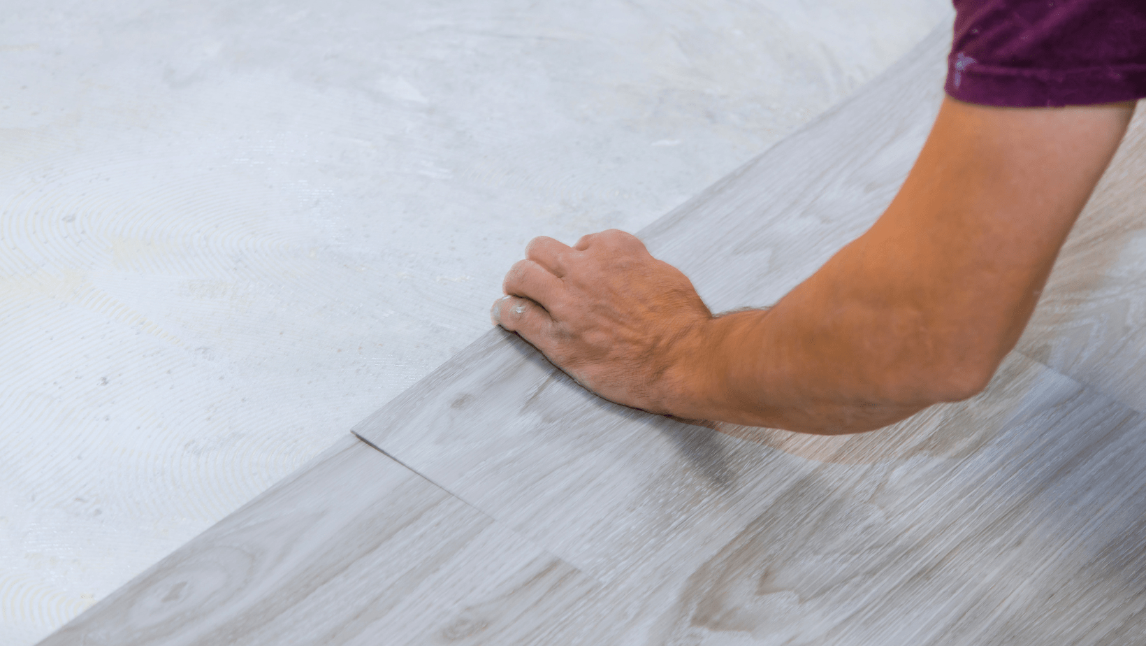 carpenter installing gray vinyl wood plank flooring