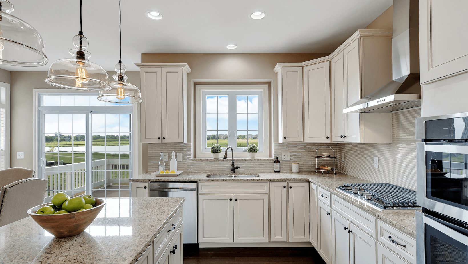 kitchen with white cabinets and light countertops lit up with recessed and hanging lights