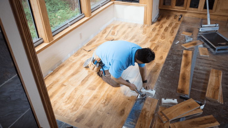 carpenter in a blue polo patching a wooden floor