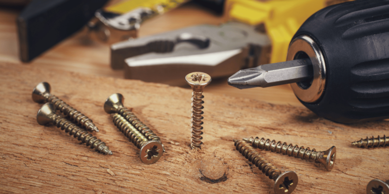 closeup of wood screws and a drill